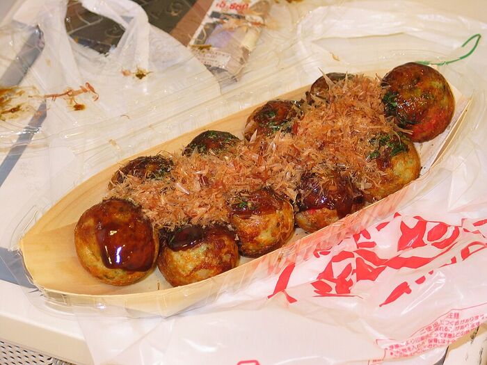 Takoyaki com molho e katsuobushi — bolinhos de polvo típicos de Osaka